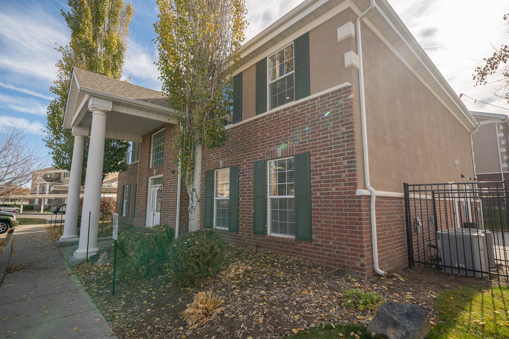 a brick house with green shutters and a tree in front of it