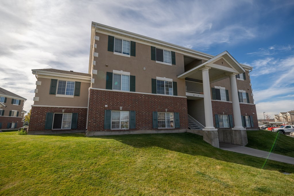 an apartment building with a green lawn and a blue sky