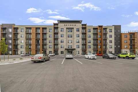 A parking lot in front of a multi-story apartment building named Reverie.