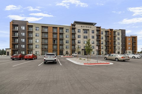 A parking lot in front of a multi-story apartment building.