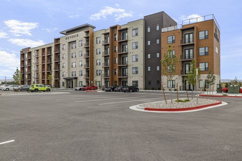 A parking lot in front of a multi-story apartment building.