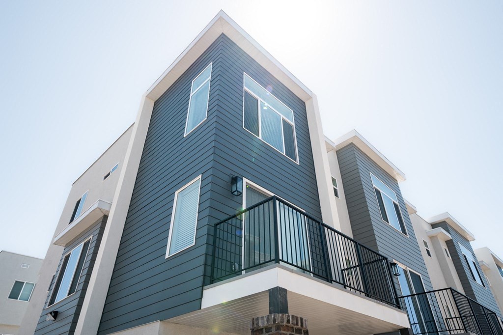 a row of apartments with blue siding and a blue sky in the background