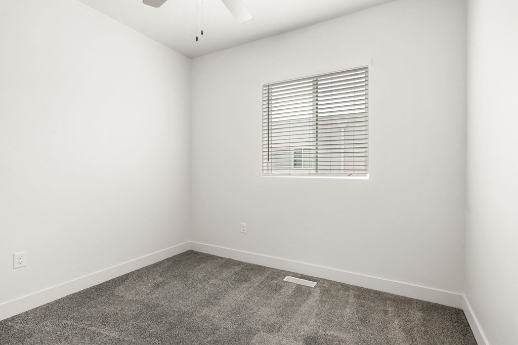 a bedroom with white walls and a window