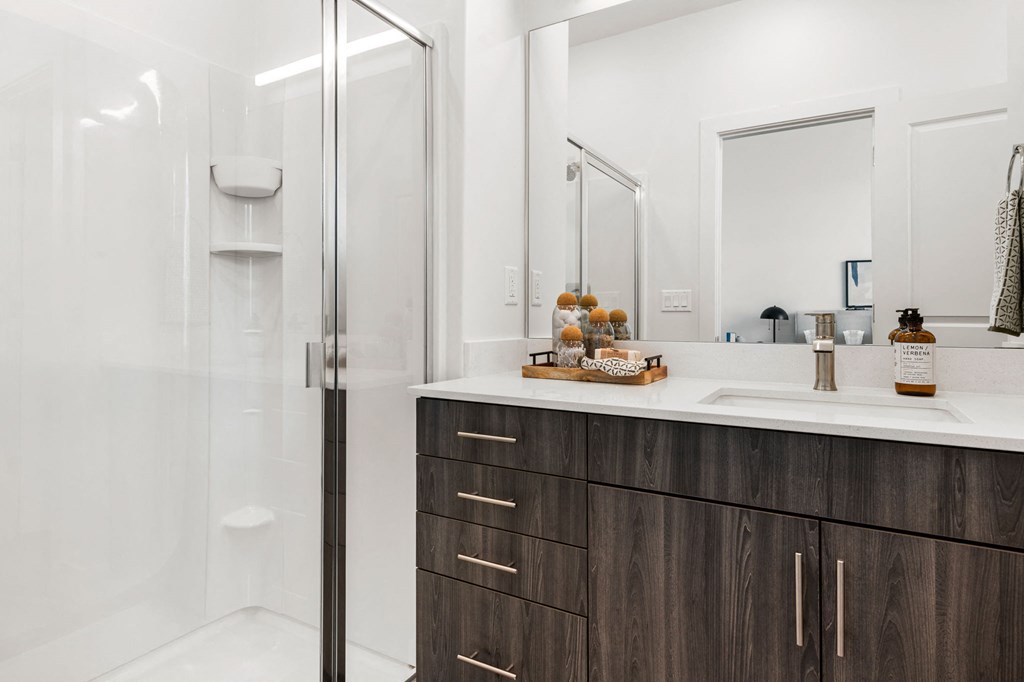 a bathroom with white walls and a wooden vanity with a white countertop