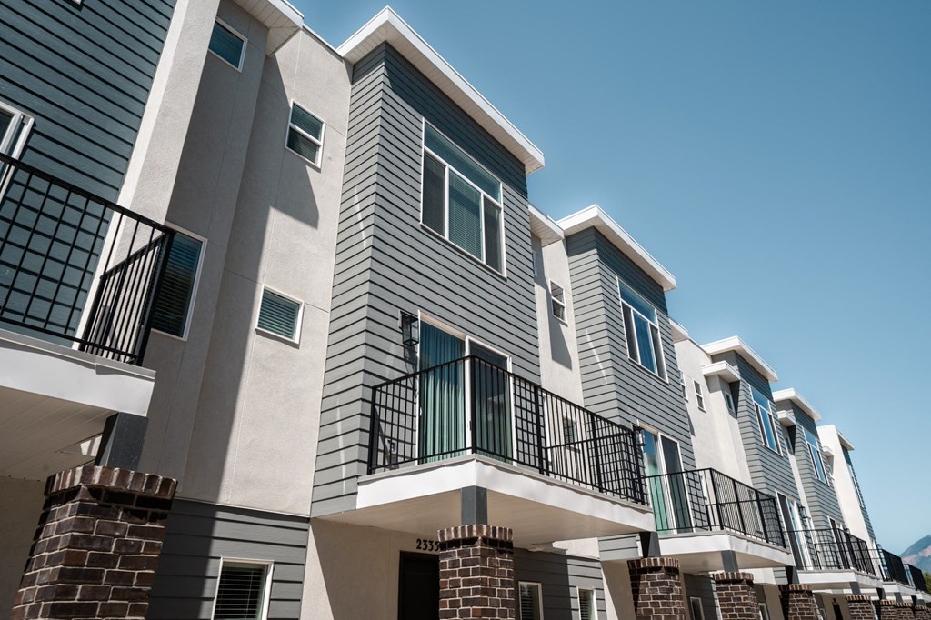 a row of apartment buildings with grey siding and blue windows