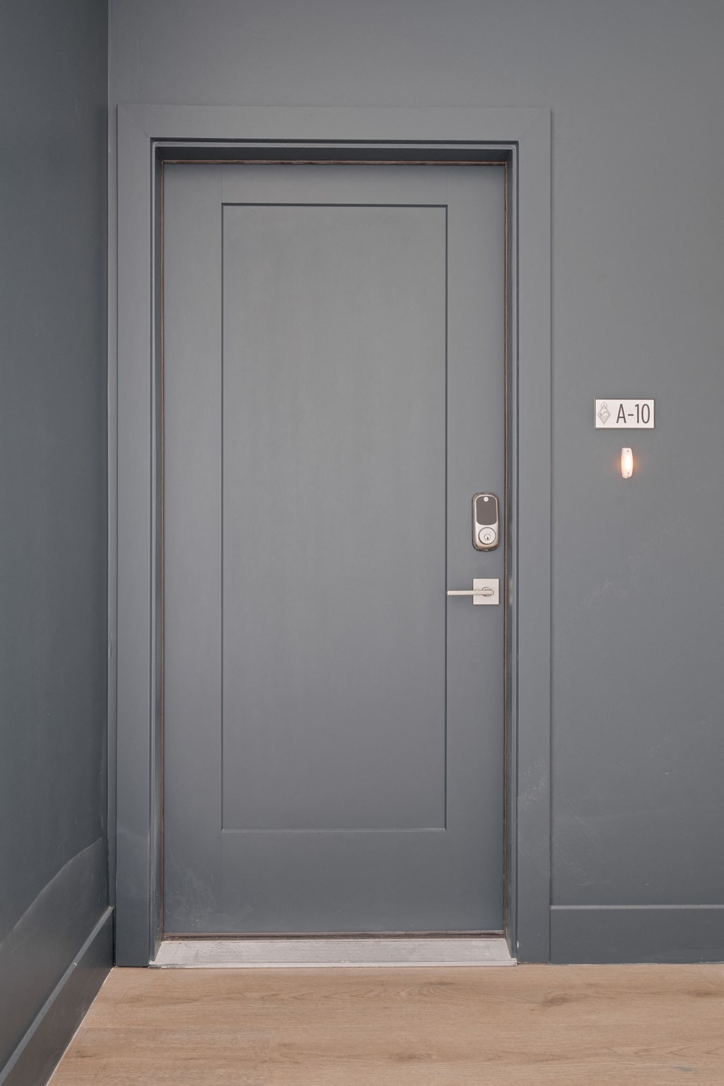 a gray door with a white door frame and a wooden floor