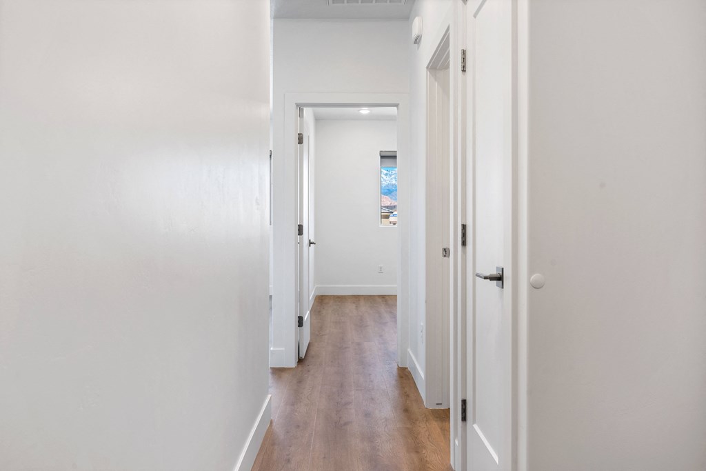an empty hallway with white walls and wood floors