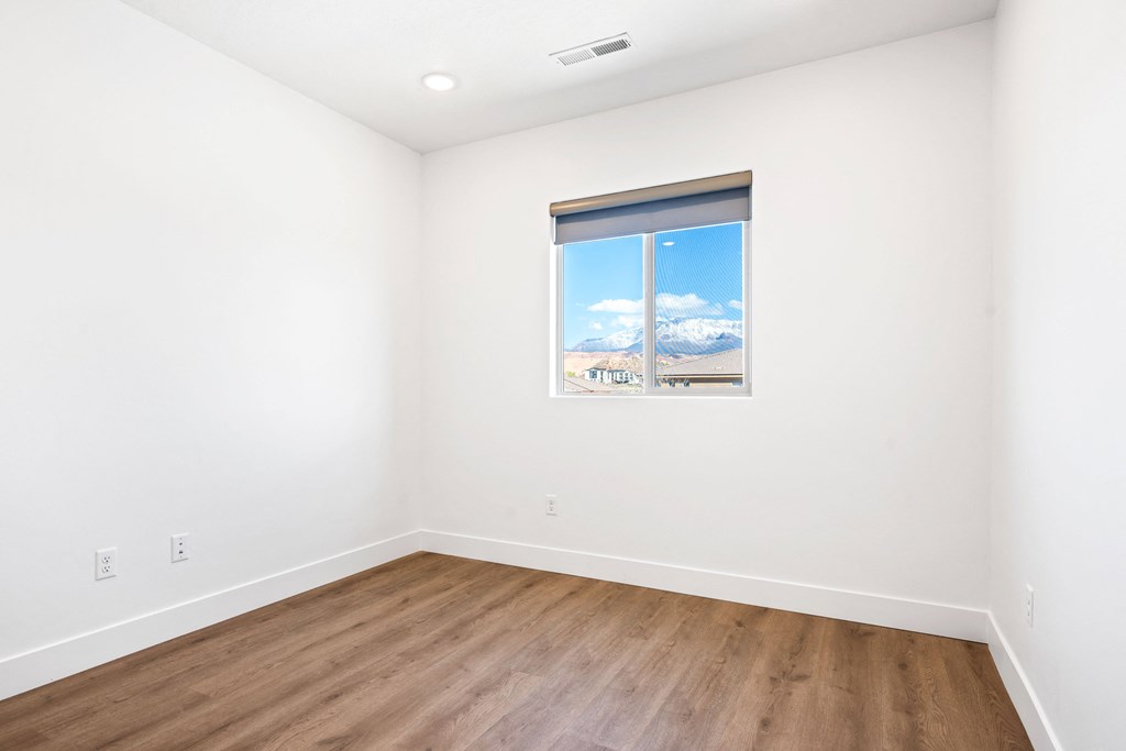 a room with white walls and wood floors and a window