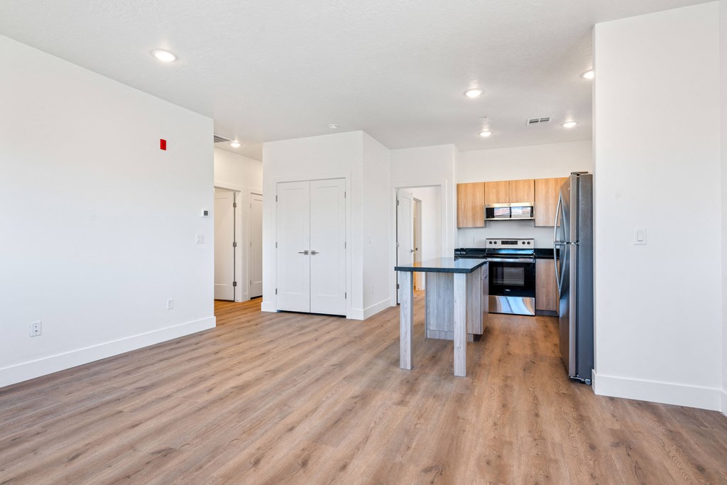 a renovated living room and kitchen with wood flooring and white walls