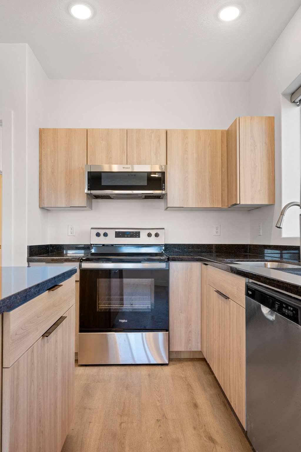 a kitchen with wooden cabinets and black counter tops and stainless steel appliances