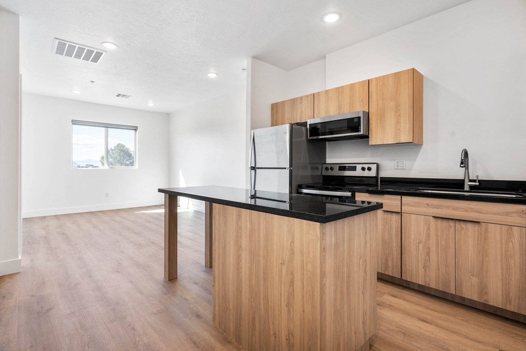 a kitchen with a black counter top and wooden cabinets