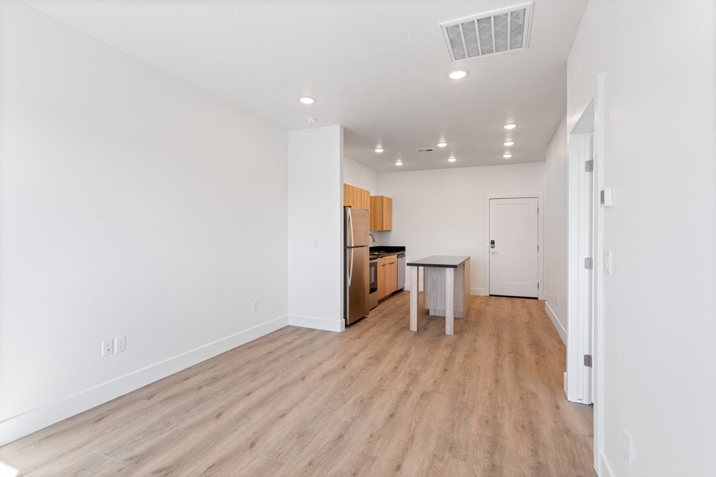 a living room and kitchen with white walls and wood flooring