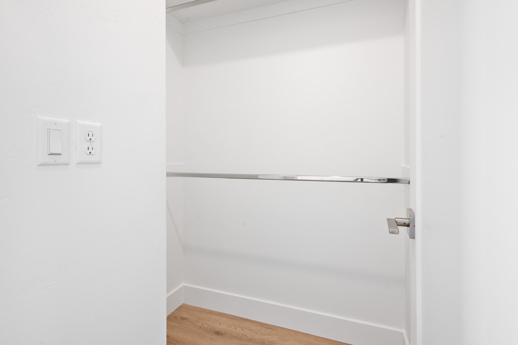 an empty closet in a white room with a door open