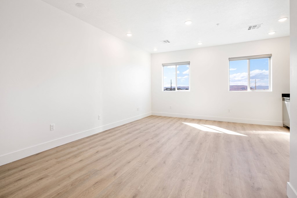 an empty living room with wood floors and white walls