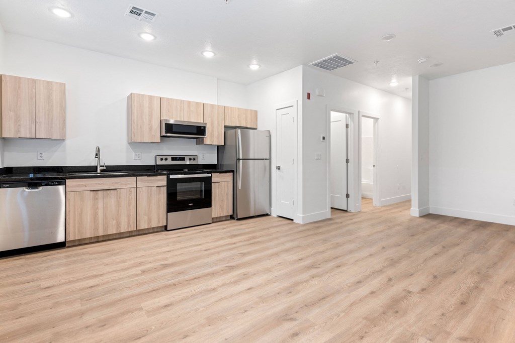 an empty kitchen with wood flooring and stainless steel appliances