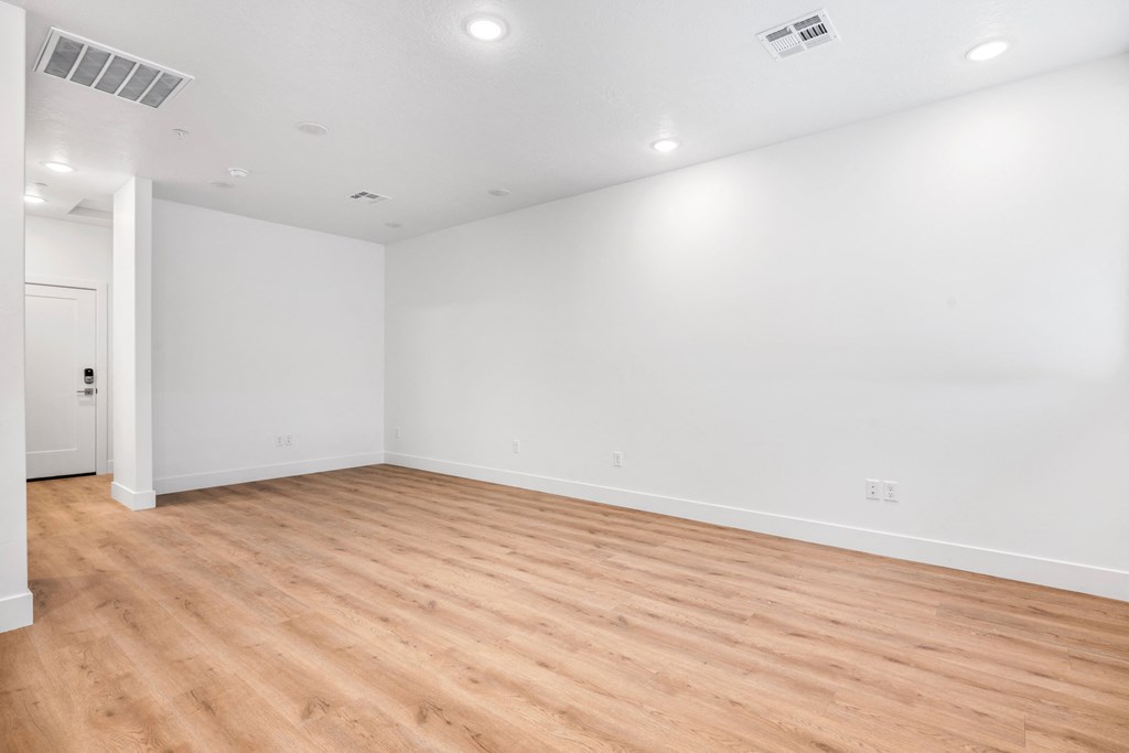 an empty living room with wood floors and white walls