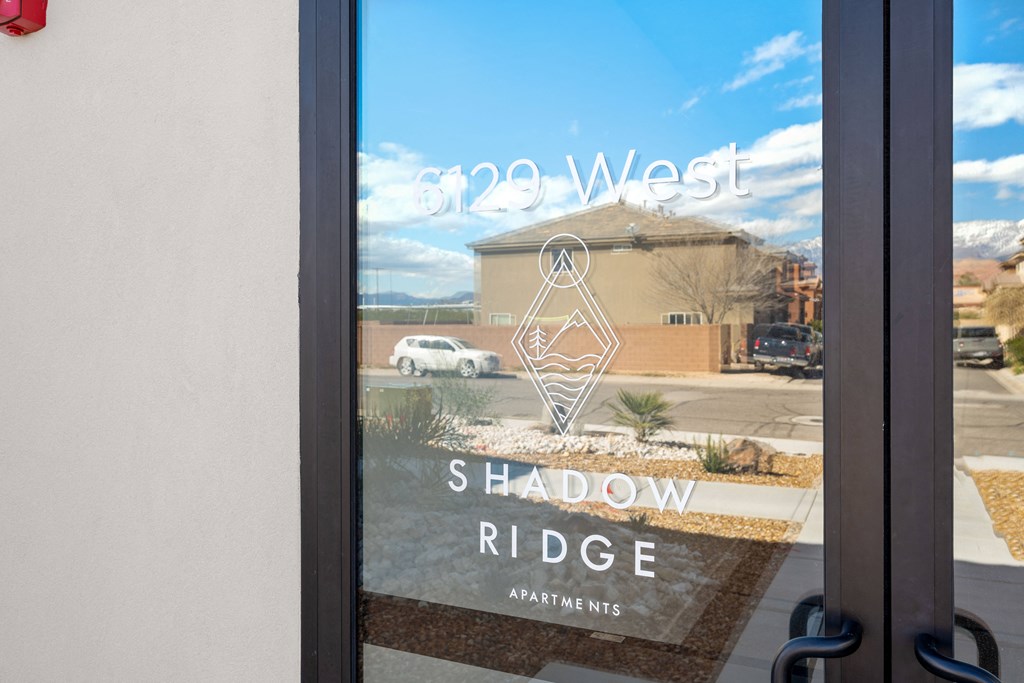 a window with a reflection of a building with a shadow ride sign on it