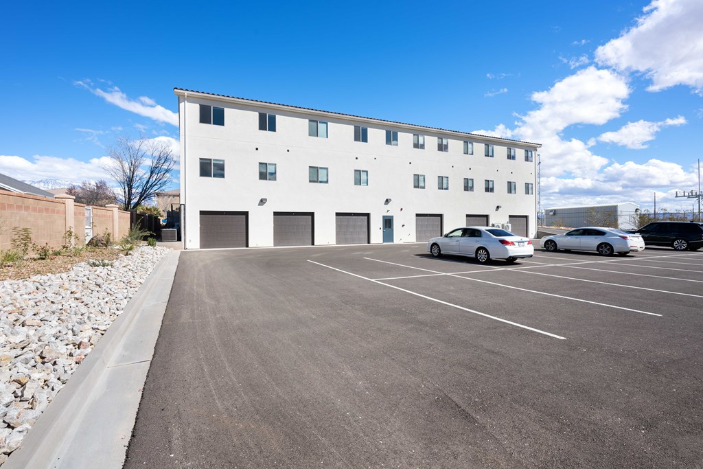 an empty parking lot with cars in front of a white building