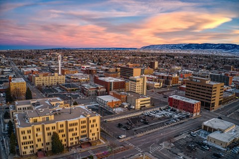 A cityscape with buildings and roads under a pink and blue sky.