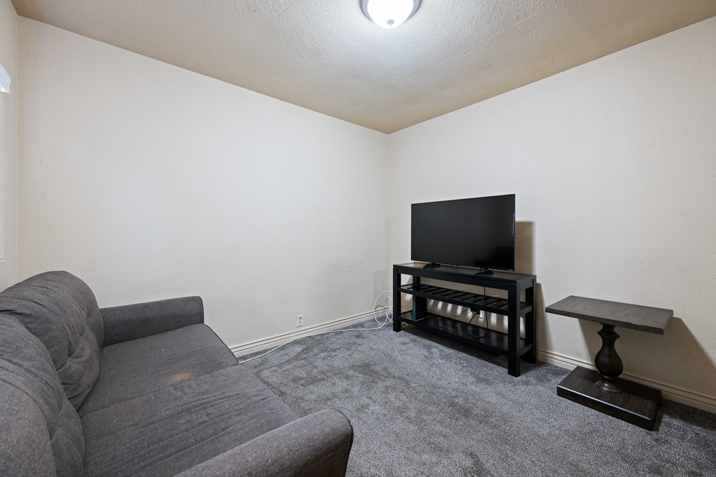 A grey sofa sits in a living room with a television and a small table.