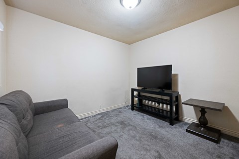 A grey sofa sits in a living room with a television and a small table.