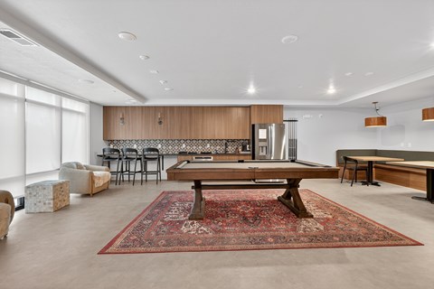 A living room with a rug on the floor and a dining table in the middle.
