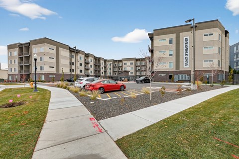 A red car is parked in a parking lot in front of a building with the name "REVERWALL CAVE" on it.
