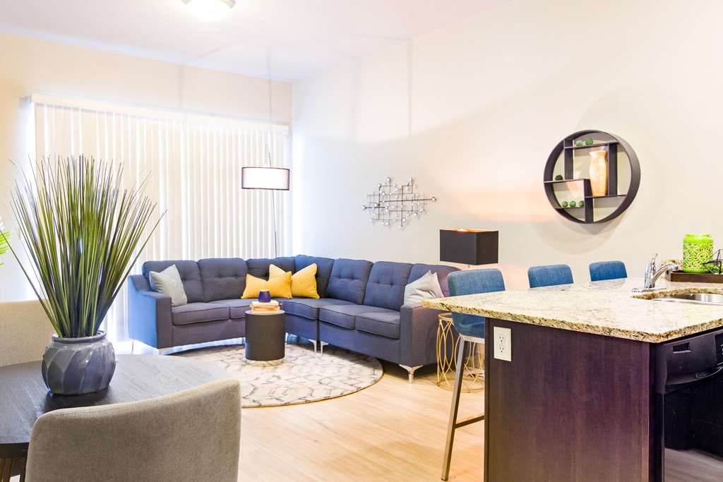 a living room with blue couches and a kitchen with a bar and a table at Sugar House Apartments By Urbana, Salt Lake City, UT, 84105