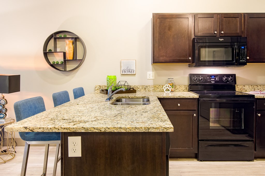 a kitchen with a granite counter top and black appliances at Sugar House Apartments By Urbana, Salt Lake City, UT, 84105
