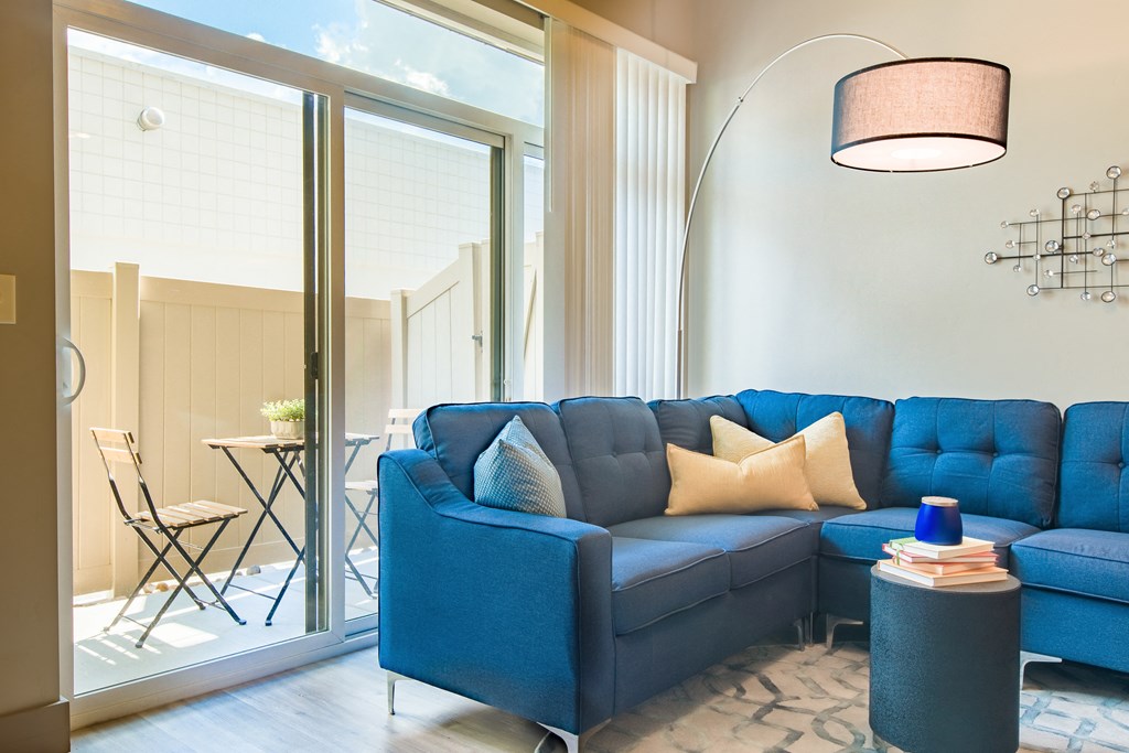 a living room with a blue couch and a large window at Sugar House Apartments By Urbana, Salt Lake City, UT, 84105
