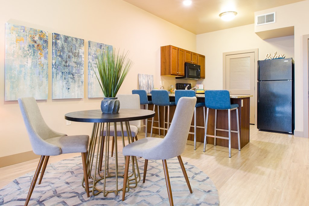 a dining room with a table and chairs and a kitchen with a refrigerator at Sugar House Apartments By Urbana, Salt Lake City, UT, 84105