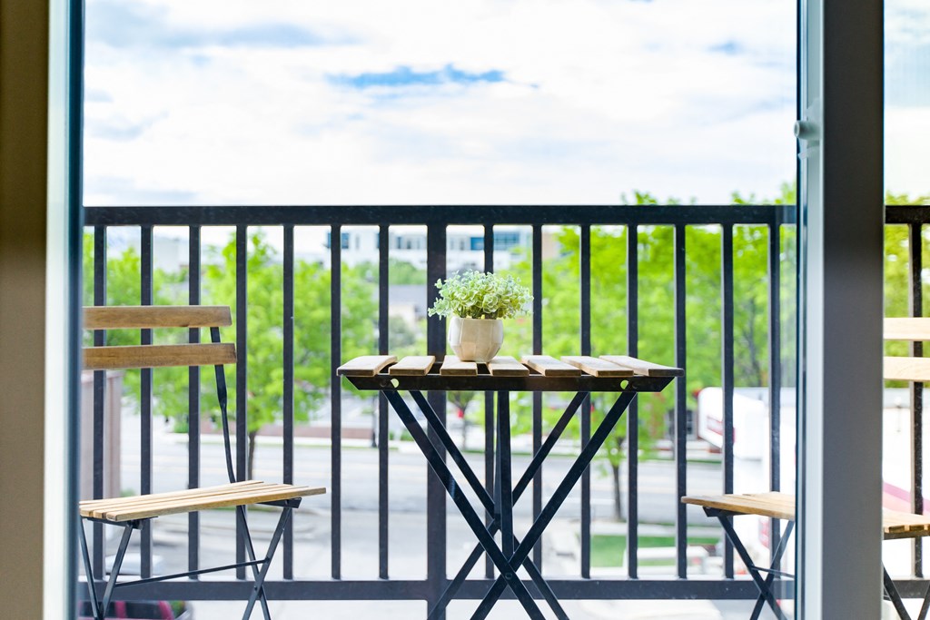 a patio with a table and chairs on a balcony at Sugar House Apartments By Urbana, Salt Lake City, UT, 84105
