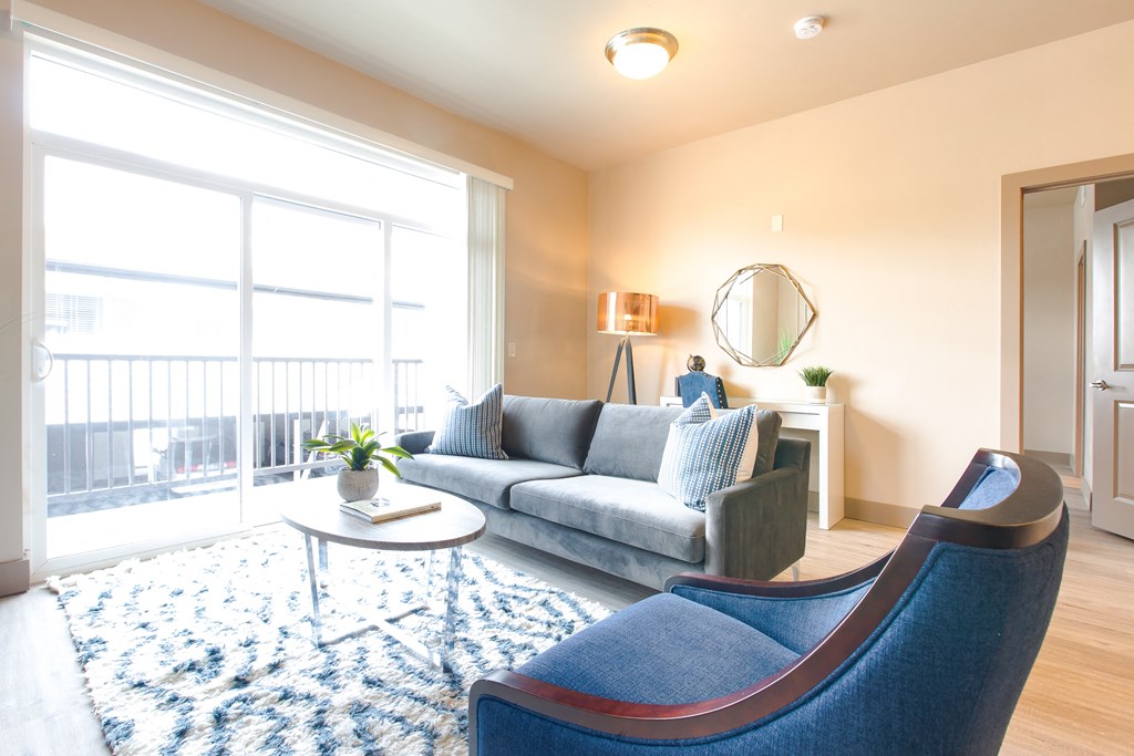 a living room with a large window and blue chairs at Sugar House Apartments By Urbana, Salt Lake City, UT, 84105