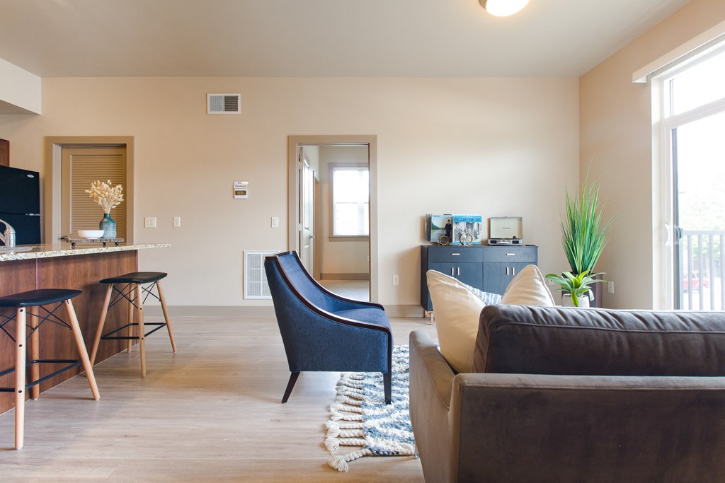 a living room with a couch chair and a kitchenette in the background at Sugar House Apartments By Urbana, Salt Lake City, UT, 84105
