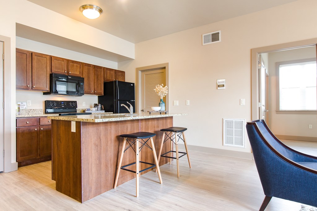 a kitchen with an island and stools at Sugar House Apartments By Urbana, Salt Lake City, UT, 84105