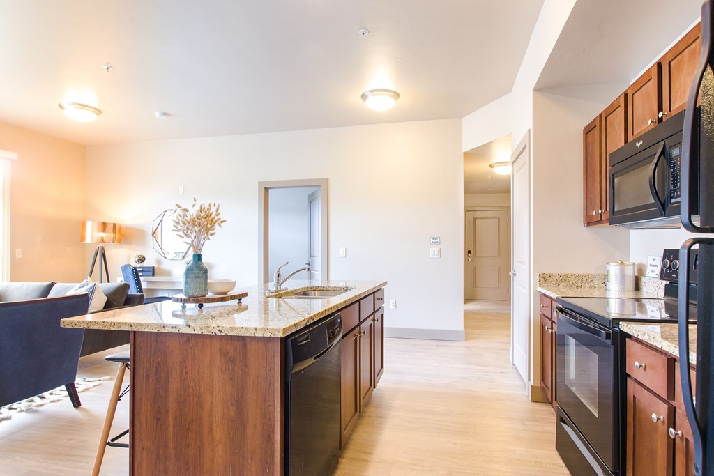 a kitchen with an island and a living room in the background at Sugar House Apartments By Urbana, Salt Lake City, UT, 84105