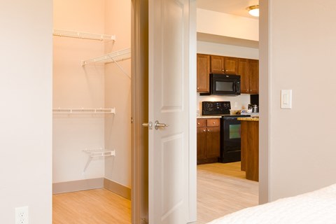 a bedroom door open to a kitchen with a sink and a microwave