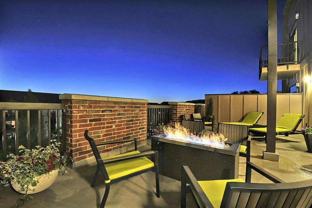 a fire pit and lounge area on the patio of an apartment building at night at Sugar House Apartments By Urbana, Salt Lake City, UT, 84105