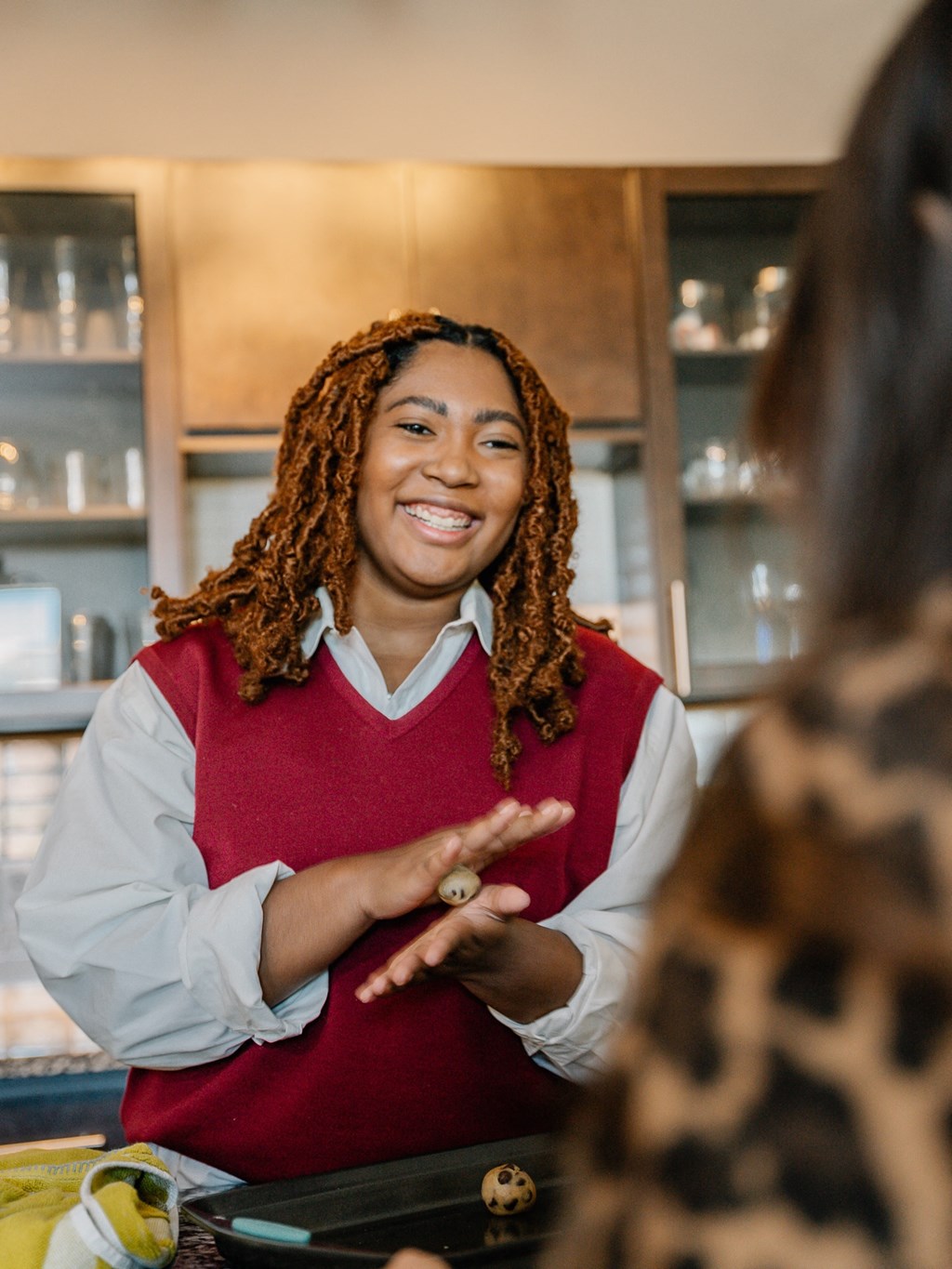 a woman talking to two other women in a kitchen