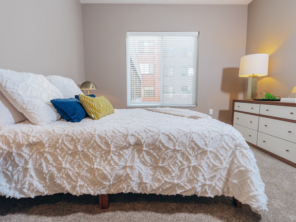 a bedroom with a bed and a dresser and a window