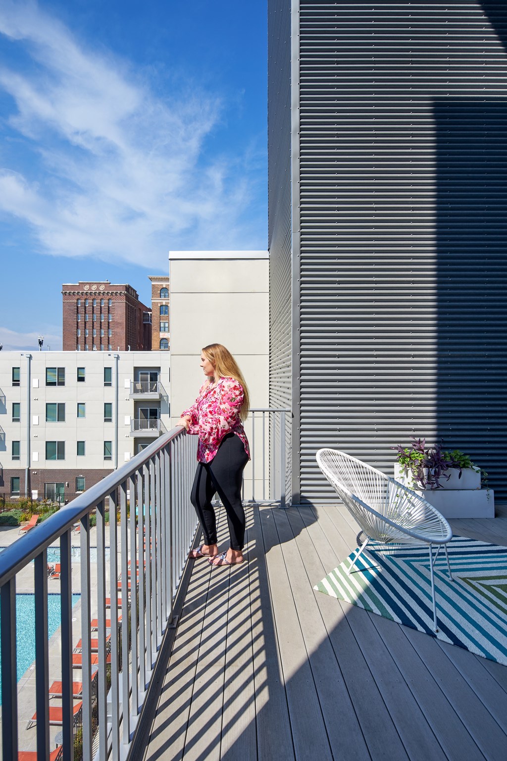 a woman standing on a balcony overlooking a swimming pool