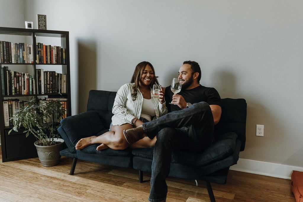 a man and woman sitting on a couch drinking wine