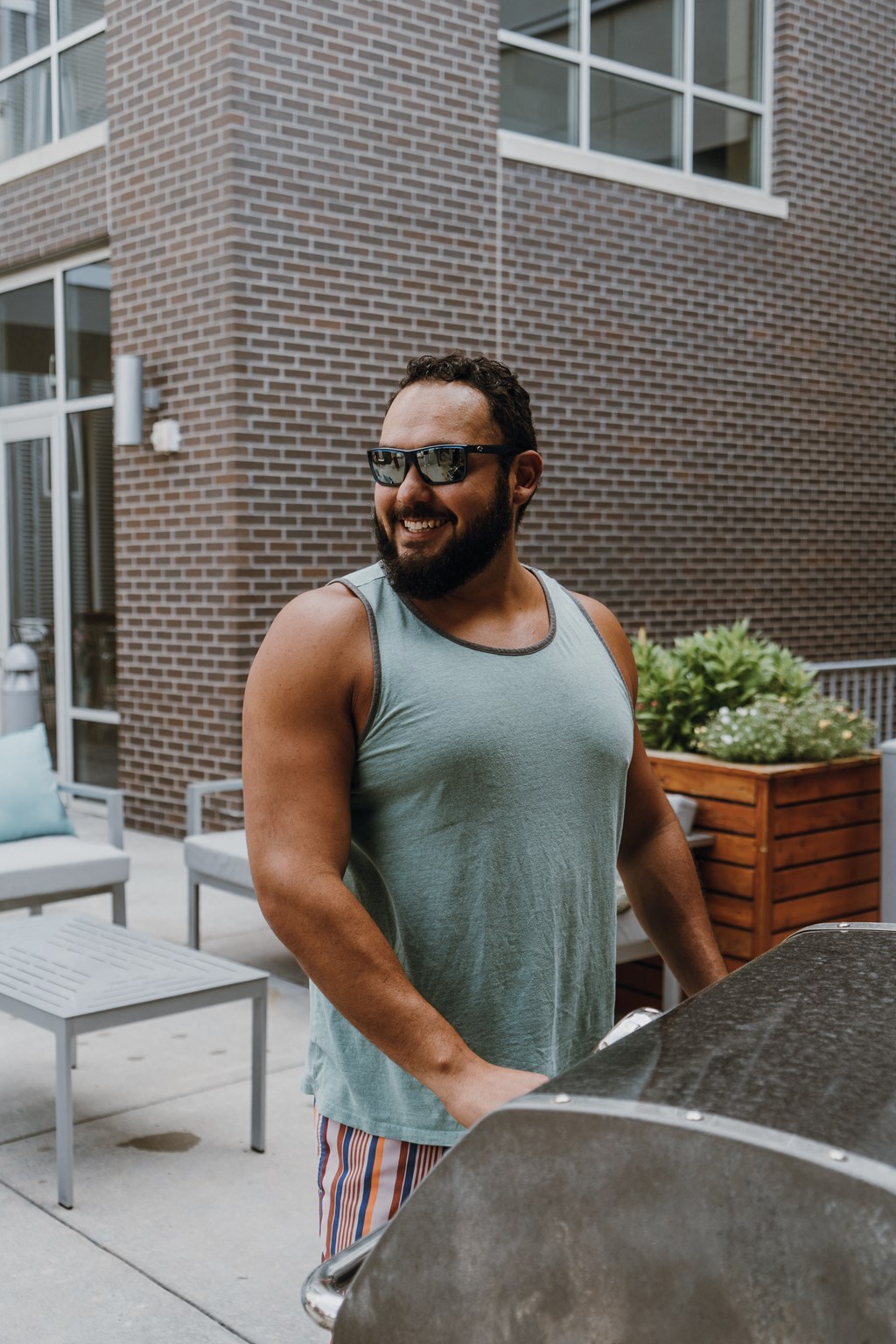a man wearing a tank top and sunglasses standing next to a car