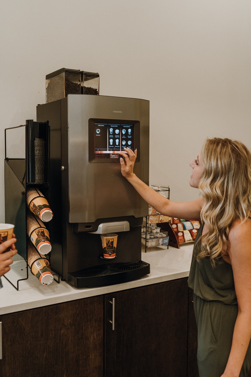 a woman is reaching for a coffee machine in a coffee shop