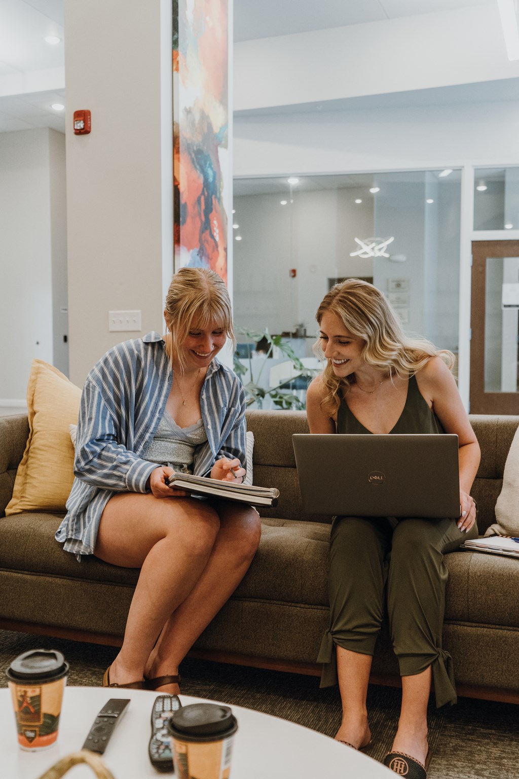 two women sitting on a couch looking at a laptop computer