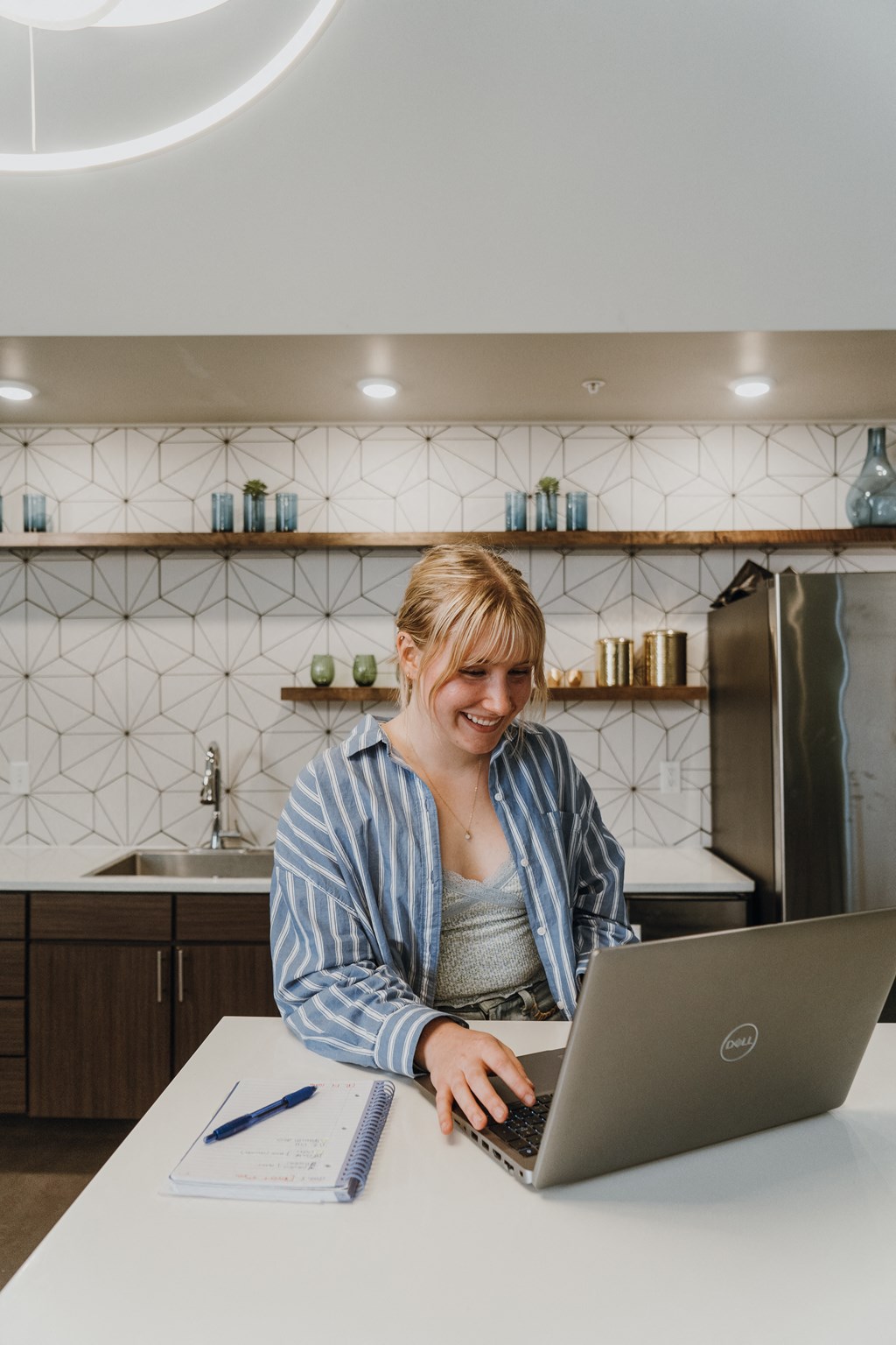 a woman sitting at a kitchen counter using a laptop computer