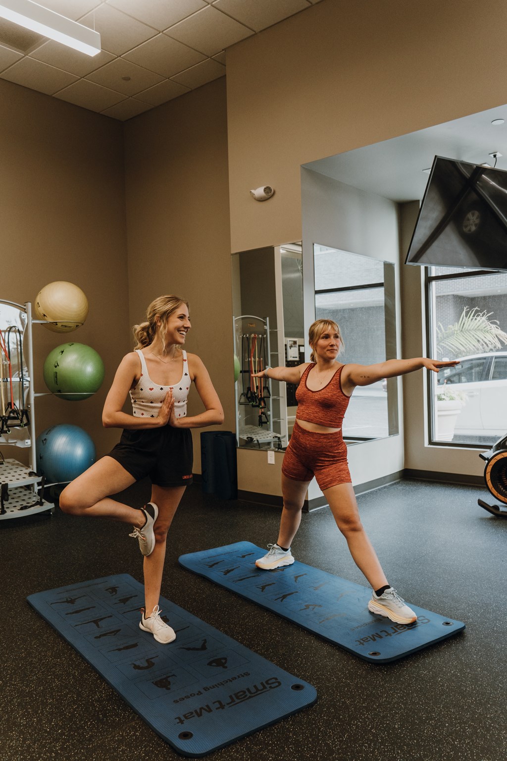 two women are standing on yoga mats in a gym