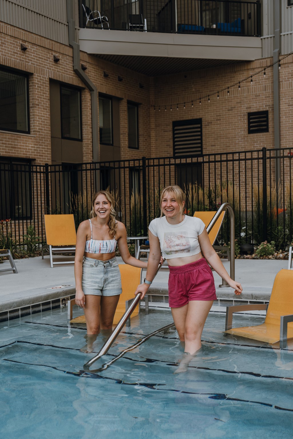 two women walking into a swimming pool         in