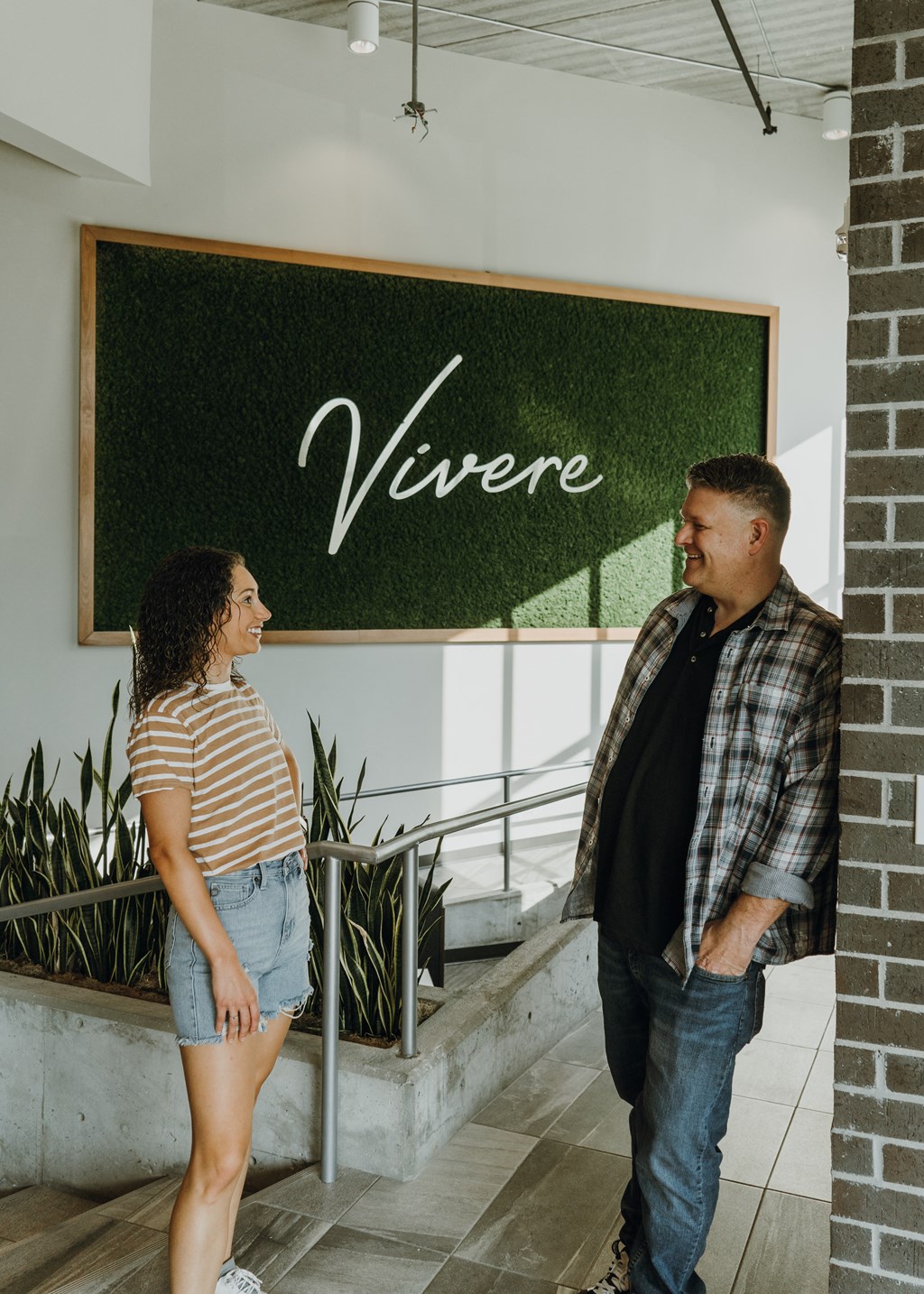 a man and a woman standing in front of a green sign