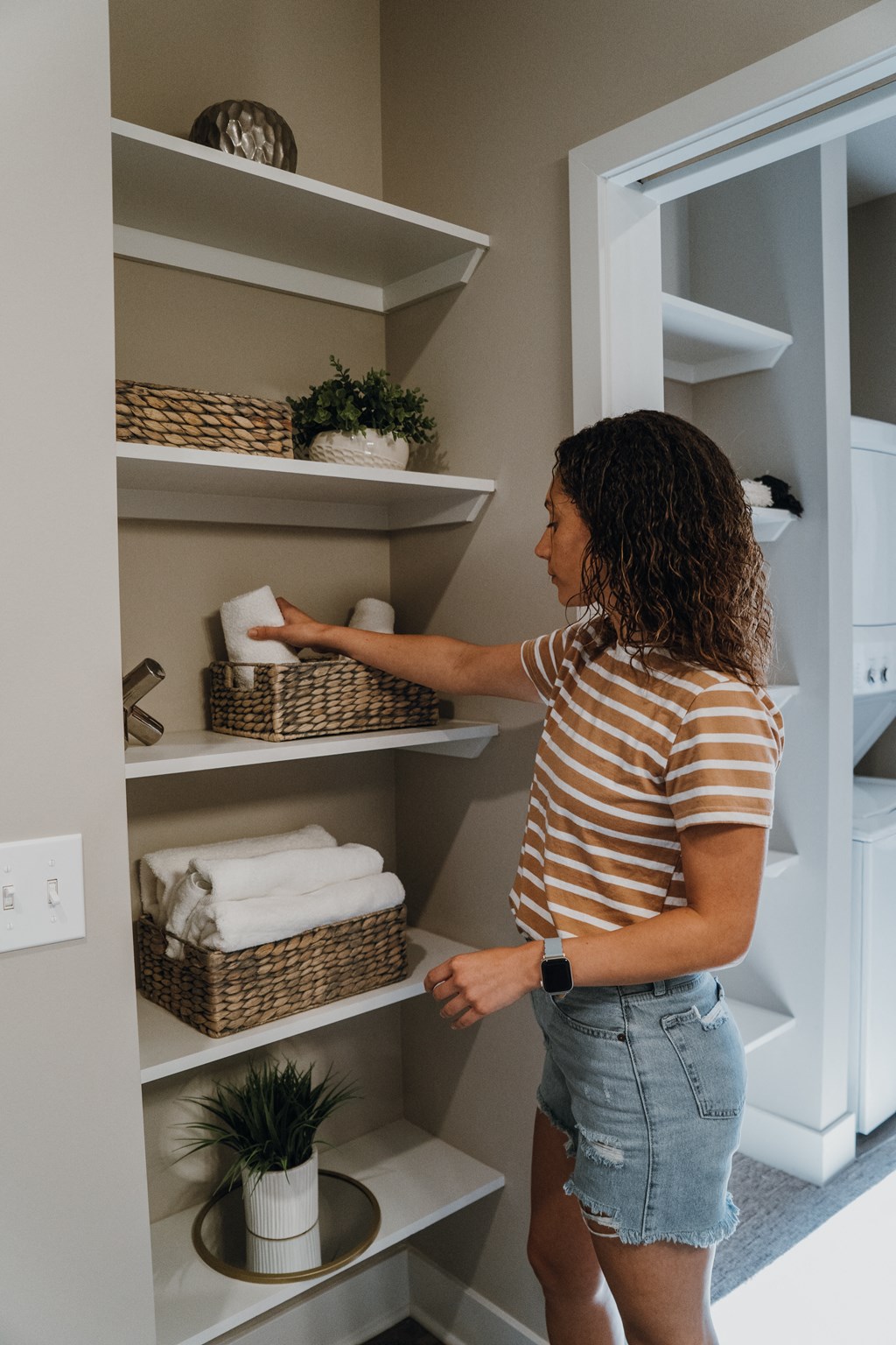 a woman putting towels into a linen closet